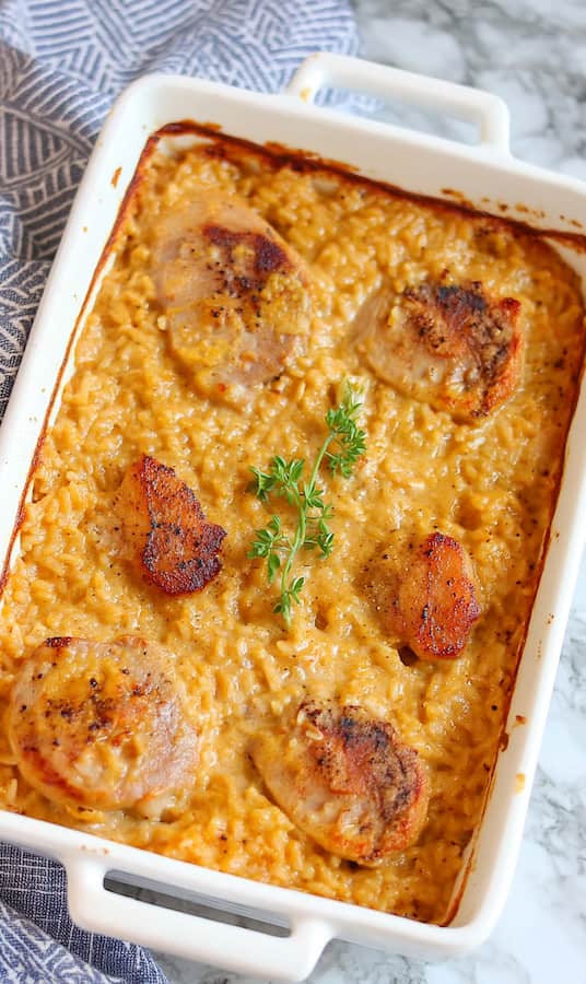 overview shot of a casserole with rice and thin boneless pork chops in a white rectangular ceramic dish